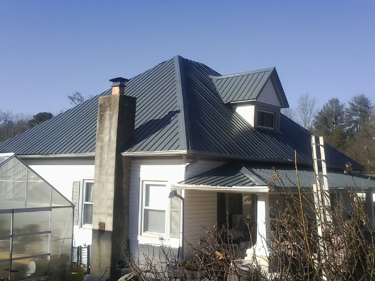 Dark blue standing seam metal roof on a white farmhouse with dormer — Slate & Tile Roof Repair by Roofing Brothers in Free Union