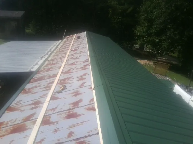 Old rusted panels beside newly installed green metal roofing — Wind Damage Roof Repair by Roofing Brothers in Free Union