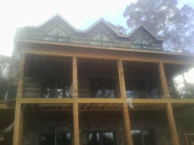 Dormers and porch framing on a large log home under construction — Roof Coating work by our crew in Free Union