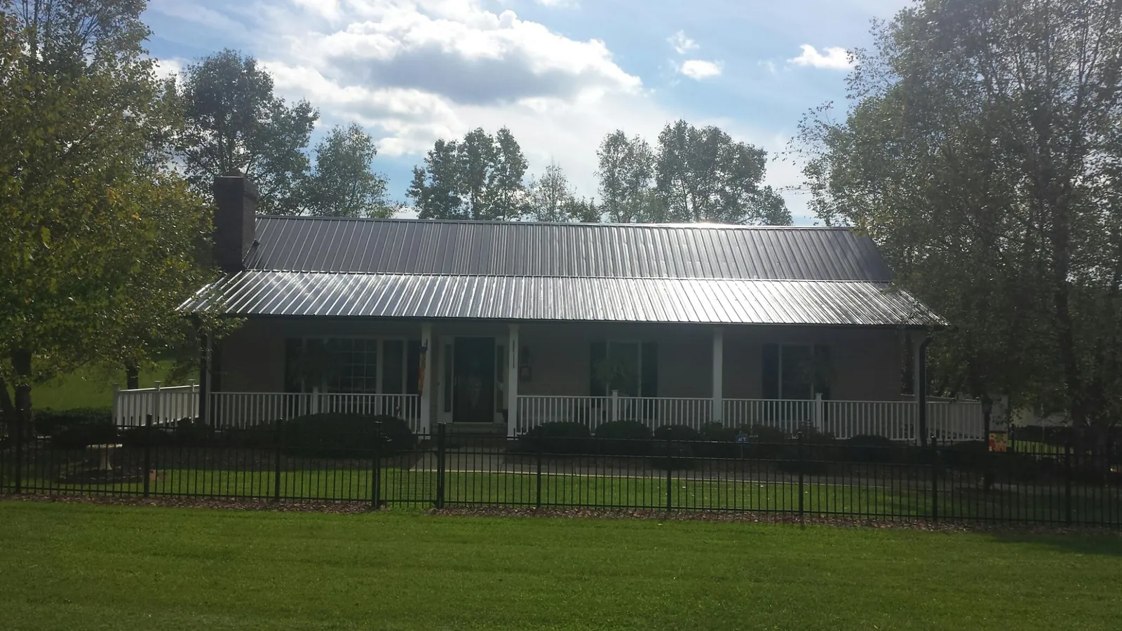 Gray metal roof on a brick ranch with a full width front porch — Gutter Guard Installation work by our crew in Free Union