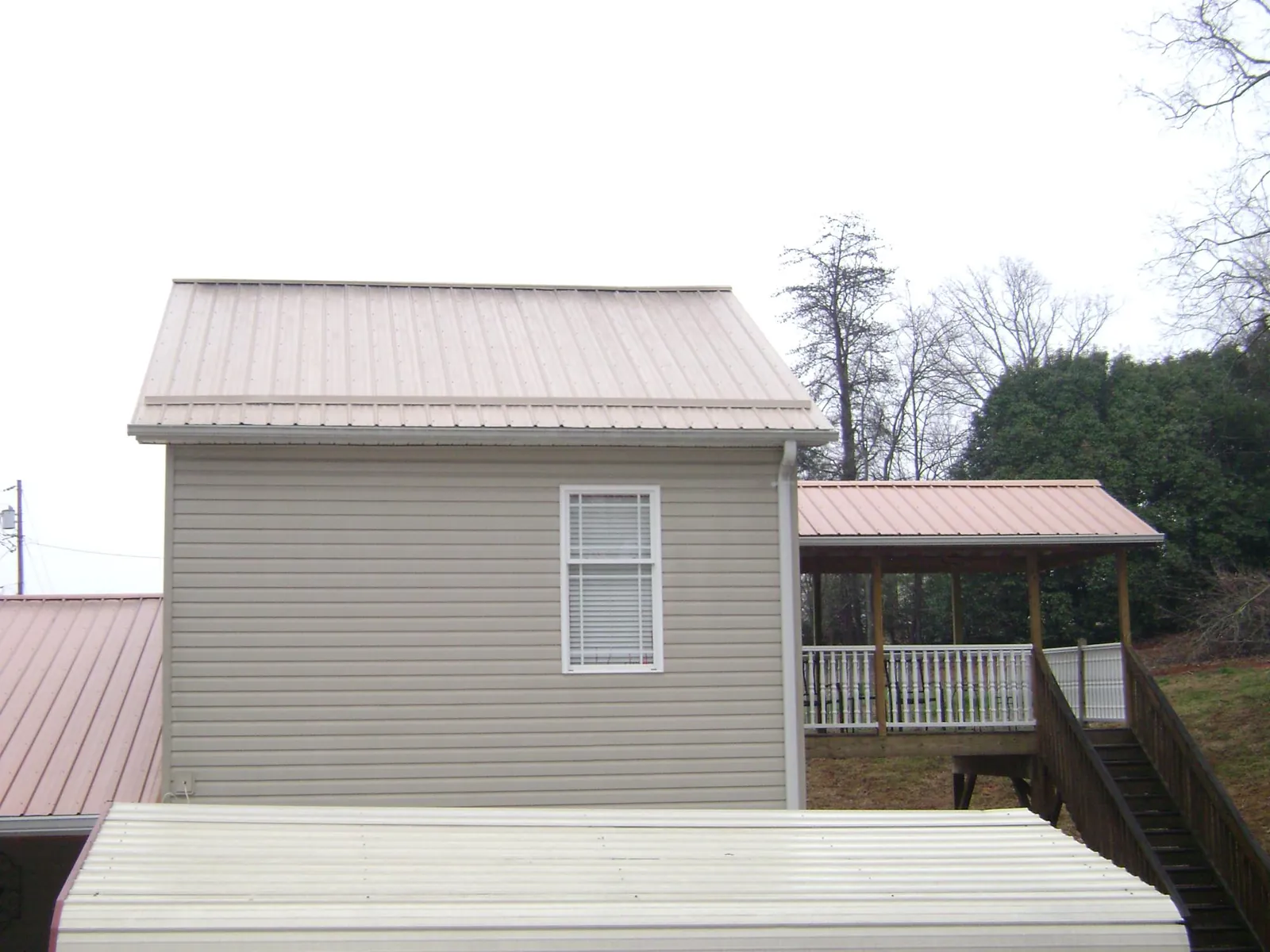 Tan metal roofs on a two story addition and attached porch, from a Roof Replacement job in Free Union