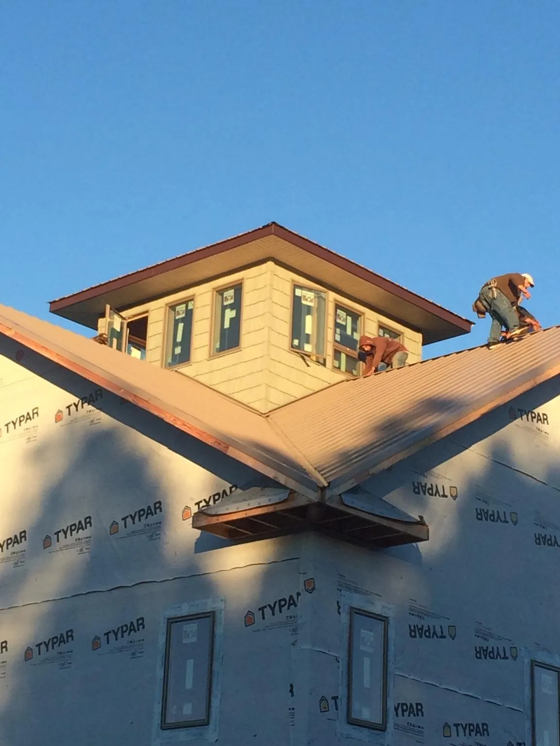 Roofers working around a rooftop cupola on a new metal roof at sunset — Roof Waterproofing in Free Union by Roofing Brothers